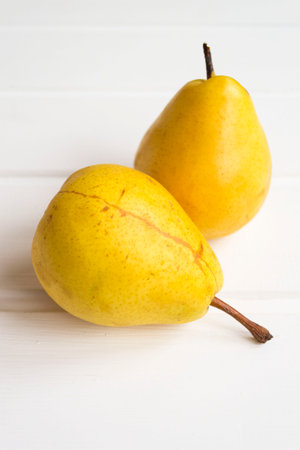 Pair of pears on a white wooden background. Soft focus. Vertical.