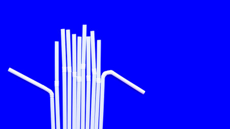 Scattered white plastic tubules for juice and cocktails on a blue background. Disposable straws. The subject of serving. Bar accessories. Summer planet pollution concept.の写真素材