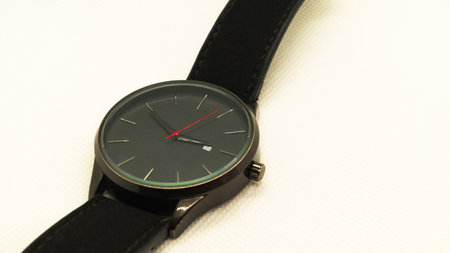 Black mens wristwatch with a red arrow on a white background. Clock without numbers. Mens accessory. Place for text.の写真素材