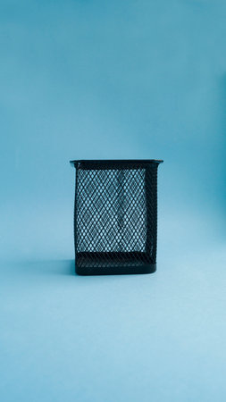 Empty metal rectangular black stationery jar isolated on light blue background. Organizer for pencils and pens. The concept of training, drawing, business. Vertical photography. Place for text.の写真素材