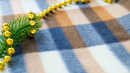 New Year and Christmas card. Christmas decorations on a blanket. A spruce branch and beads lie on a winter plaid blanket. Place for your text. Copy space. Selective focus.の写真素材