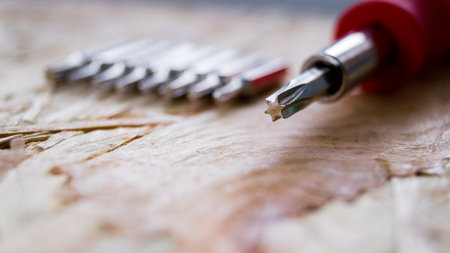 The screwdriver lies on a wooden background. Screwdriver with five edges. A set of small...