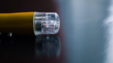 The top of the laser pointer with multiple modes on a dark background. Point to something. Childrens toy. Small yellow metal flashlight. Place for text.の写真素材