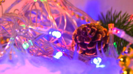 Blurred pine cone and branch and garland with colorful bright lights. Good New Year spirit. Blank...