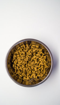 Dry food for cats of various shapes in a metal bowl on a white glossy background. Pet food concept. Taking care and caring for pets. Mans best friends. Place for text. Selective focus.の写真素材