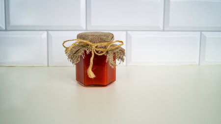 Organic fresh liquid honey in a glass jar with a burlap lid on a light background. Honey-raspberry soufflÃ© of our own production. Healthy eating.の写真素材