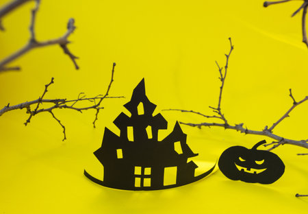 Halloween and decoration concept - bats, pumpkins, gloomy paper house, gloomy black tree branches on a yellow background. Folded paper origami art. Halloween background with cut out batsの写真素材