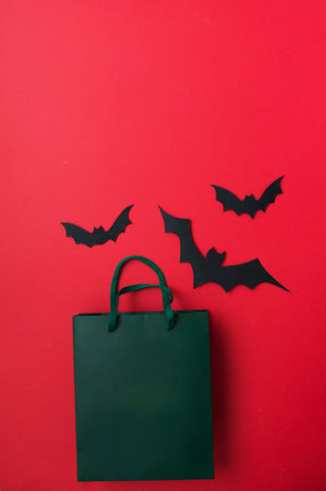 Halloween flat lay - bats and pumpkin on red background. gifts and shopping for halloween. place for text.holidays and surprises.の写真素材