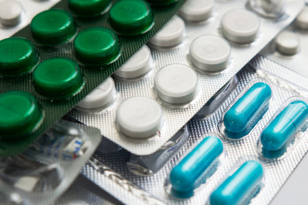 Medicinal pills on a white background. Coronavirus and isolation. Medical mercury thermometer on the background of pills and a protective mask. Medicinal medicine as background.の写真素材