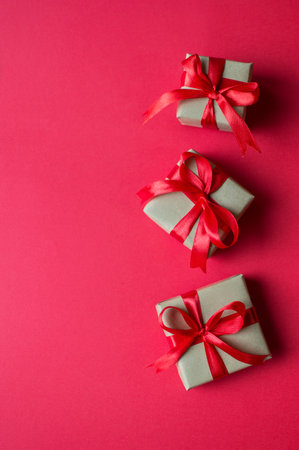 Festive concept - gifts with craft paper with a red bow on a red background. composition for christmas, new year and holidays. flat lay with place for text.の写真素材