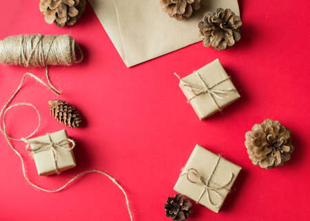 Festive concept - gift wrapping with whips and cones on a red background. composition for christmas, new year and holidays. flat lay with place for text.の写真素材