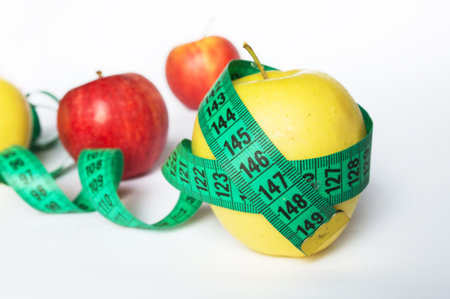 Healthy food concept - fresh fruits and measuring tape, apples and weight loss on a white...