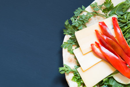 Pita bread, pepper and vegetables with cheese on a dark backgroundの写真素材