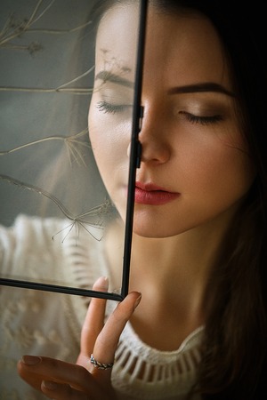 gentle girl posing fooling in vintage view through glassの写真素材