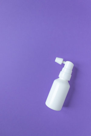 Top view of plastic ear spray bottle with nozzle on a very peri background. Auricular hygiene and...