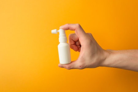 Man hand holds a white ear spray bottle. For daily clean the ears from earwax. Health care concept.