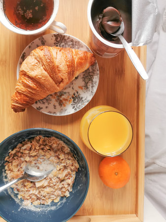 Healthy food at morning with a bowl of muesli, fresh orange juice and a cup of chikory. And unhealthy french croissant.の写真素材