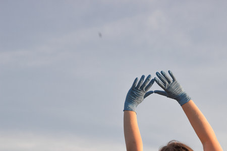 Doctor's hands in blue medical surgical gloves up to the clean sky. Woman hands in blue latex gloves. Medicine ambulance worker in Ukraine, save life concept.の写真素材