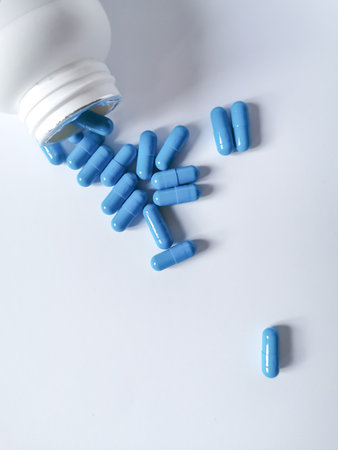 Group of blue capsules are poured out of the bottle. Copy space for text.