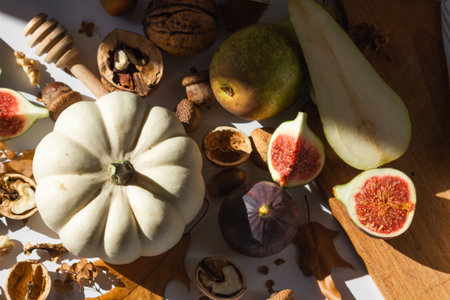 Autumn still-life with white pumpkin, sliced figs, walnuts and pears on wooden cutting board. Healthy eating concept.の写真素材