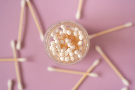 White cotton buds for ears care isolated on a pink background, top view. Concept of daily ear...