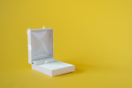 White open gift box isolated on yellow background. Empty jewelry box, place for a gift for birthday...