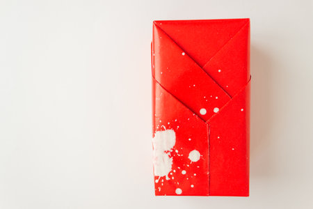 Gift box is wrapped in red paper in splashes of white paint. isolated on white background. high...