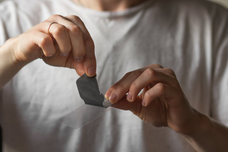 Man's hands holds black nose patch in front of him, ready for use. Married male using cosmetics to clean pore skin and remove blackheads on nose. Daily morning routine and skin care concept.の写真素材