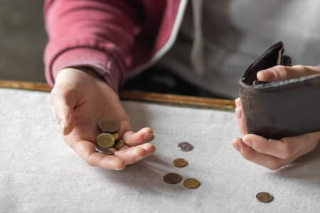 Young man counting coins on table in a period of crisis. Poor man holds handful of poland coins and...