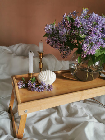 Folding table on the bed with candle in shell form, candels in vintage brass candlesticks and bunch...