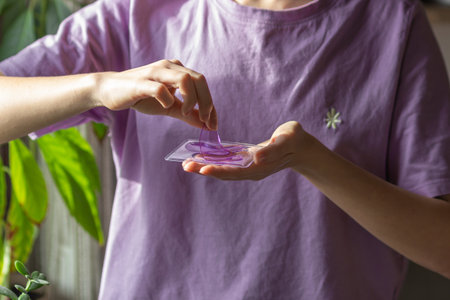 Womans hands holds purple hydrogel eye patches in front of her, ready for use cosmetics against wrinkles and puffiness.の写真素材