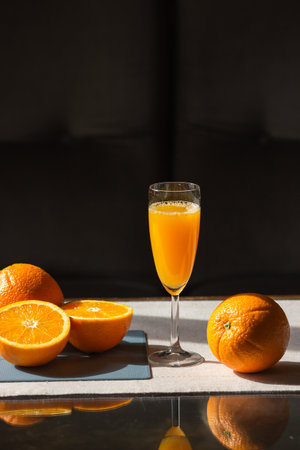 Glass of fresh squeezed orange juice with raw oranges on cutting board isolated on black background. Healthy eating.の写真素材