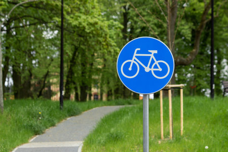 White bicycle lane road traffic sign on blue round background. Bike sign on metal pole, blur narrow...