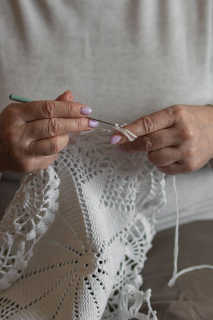 Old womans hands knitting with crochet hook. Grandma crocheting with white thread a lace tablecloth. Handicraft conceptの写真素材