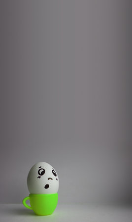 Eggs with faces photo for your design. With a place for text. Funny and cute. Egg freak in green mug with tea breakfastの写真素材