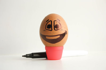 Egg with a cheerful painted face. Photo for your design. With the marker is the creative process. Place under the text. Clouds are thoughts over your head.の写真素材