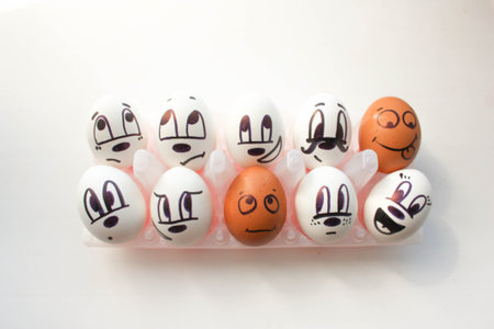 Groupmates concept. Eggs in cells with a painted face looking up. black and white. on a white...