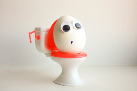 Hemorrhoid problems. Eggs with a funny painted face on the toilet. Photo for your design.の写真素材