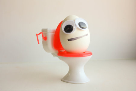 Eggs with a funny painted face on the toilet. Photo for your design.