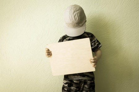 Concept of business. The child tilted his head over the plaque in a gray cap. Photo for your design. With a place under the text.の写真素材