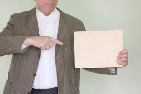 Business concept businessman. Holds an empty nameplate. Point with your finger. In the profile. Place for your text. Photo for your designの写真素材