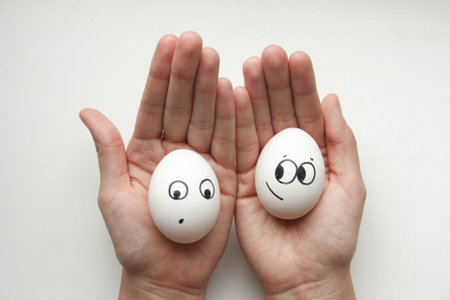 Diet concept. Female hands holding eggs with funny little faces painted. Photo for your design