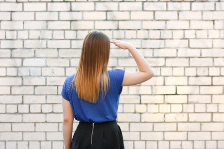 Female student concept. Beautiful girl near a brick wall. Looks into the distance. Photo for your designの写真素材