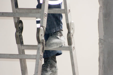 Construction concept. The worker on the ladder climbs up. Horizontal sheet orientationの写真素材