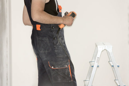 Construction concept. An electrician holds a puncher in the hands of a ladders. Horizontal sheet orientationの写真素材