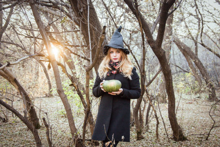 Hallow-positive, cute photo. beautiful witch and a green witch pumpkin in a forest covered with sun...