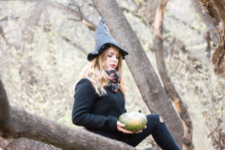 Halloween. beautiful witch and a green witch pumpkin in the forestの写真素材