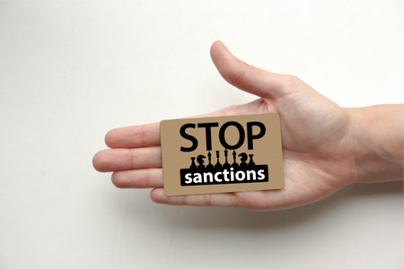 stop sanctions concept. the inscription on the wooden plaque lies on the handの写真素材