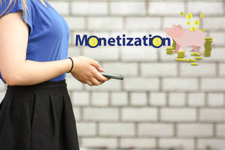 monetization concept. income from a hobby. young woman with smart phone on brick wall backgroundの写真素材