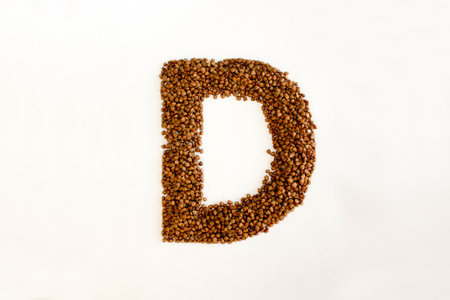 D the letter. alphabet of buckwheat porridge. buckwheat grain. concept of healthy eating. photo for your design. horizontal orientation of the sheetの写真素材